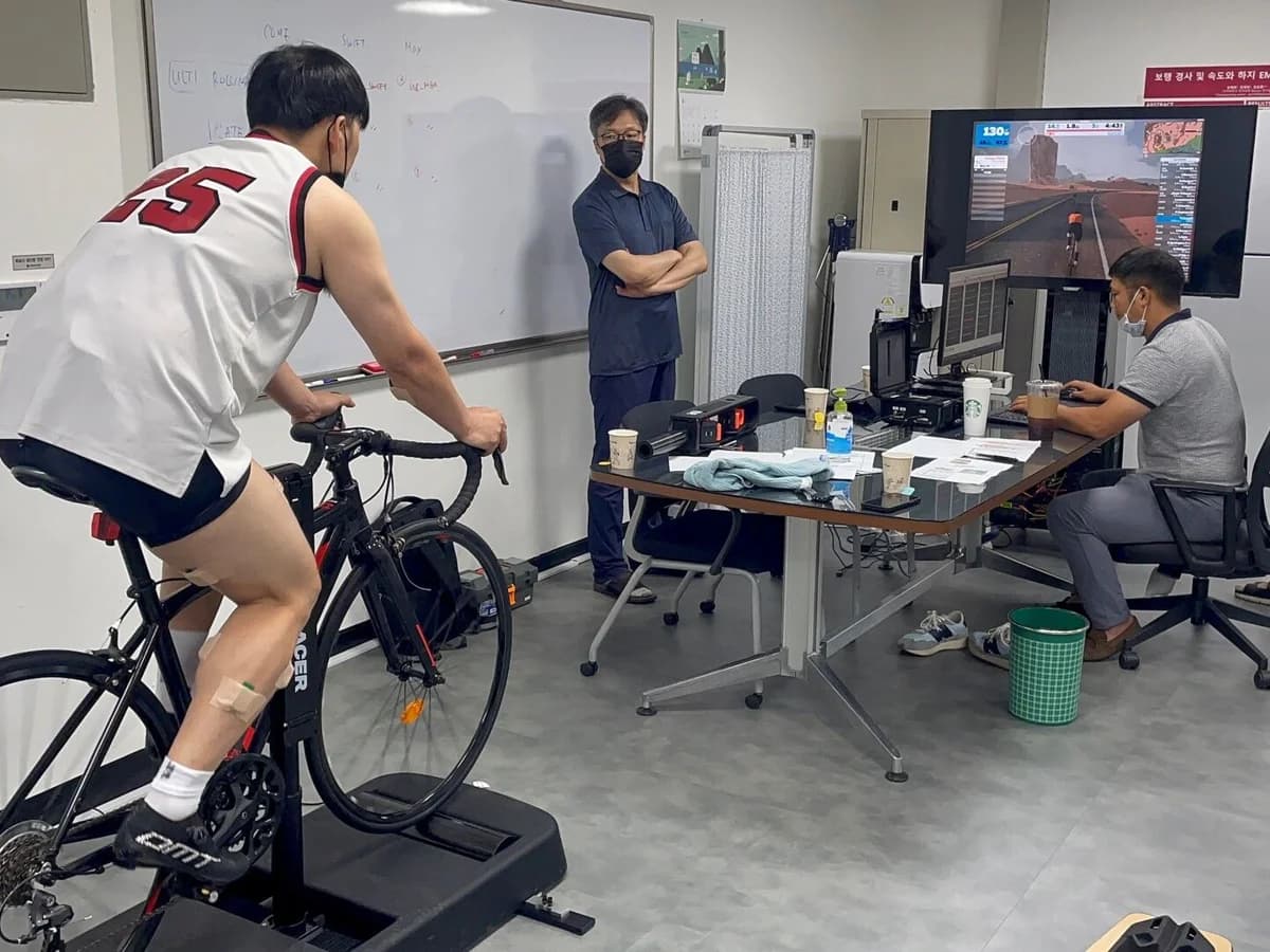 A cyclist using Ultiracer with researchers and measurement equipment in a laboratory