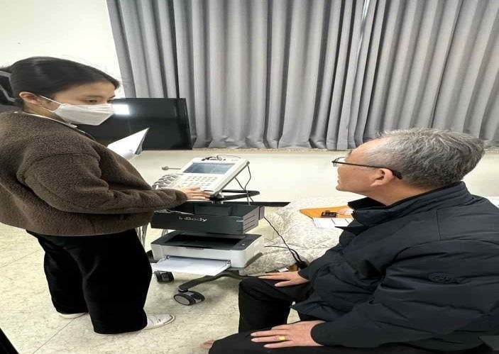A researcher in a face mask operating an InBody body composition analyzer next to a seated older man