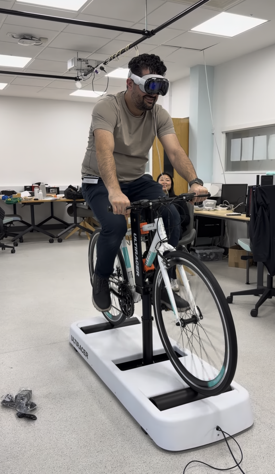 Investigador pedaleando en el entrenador Ultiracer con un casco de realidad virtual